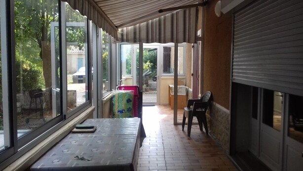 A covered outdoor area with a table, chairs, and a view of the outside. - Country home (Roquefort)