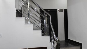 A staircase with a metal handrail and a black door at the top. - Hotel Gopal (Haridwar)