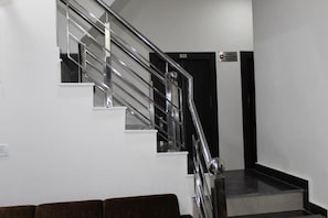 A staircase with a metal handrail and a black door at the top. - Hotel Gopal (Haridwar)