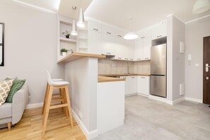 Une cuisine moderne avec des meubles blancs, un réfrigérateur en acier inoxydable et un plan de travail en bois.