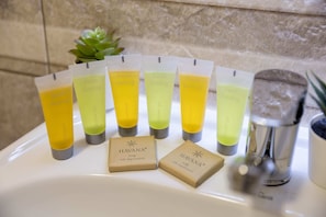 Un meuble-lavabo de salle de bain avec plusieurs flacons de savon « Havana » et une pomme de douche.