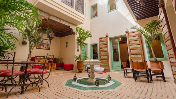A courtyard with a fountain, seating area, and a dining table. - Riad Azrur (Marrakech)