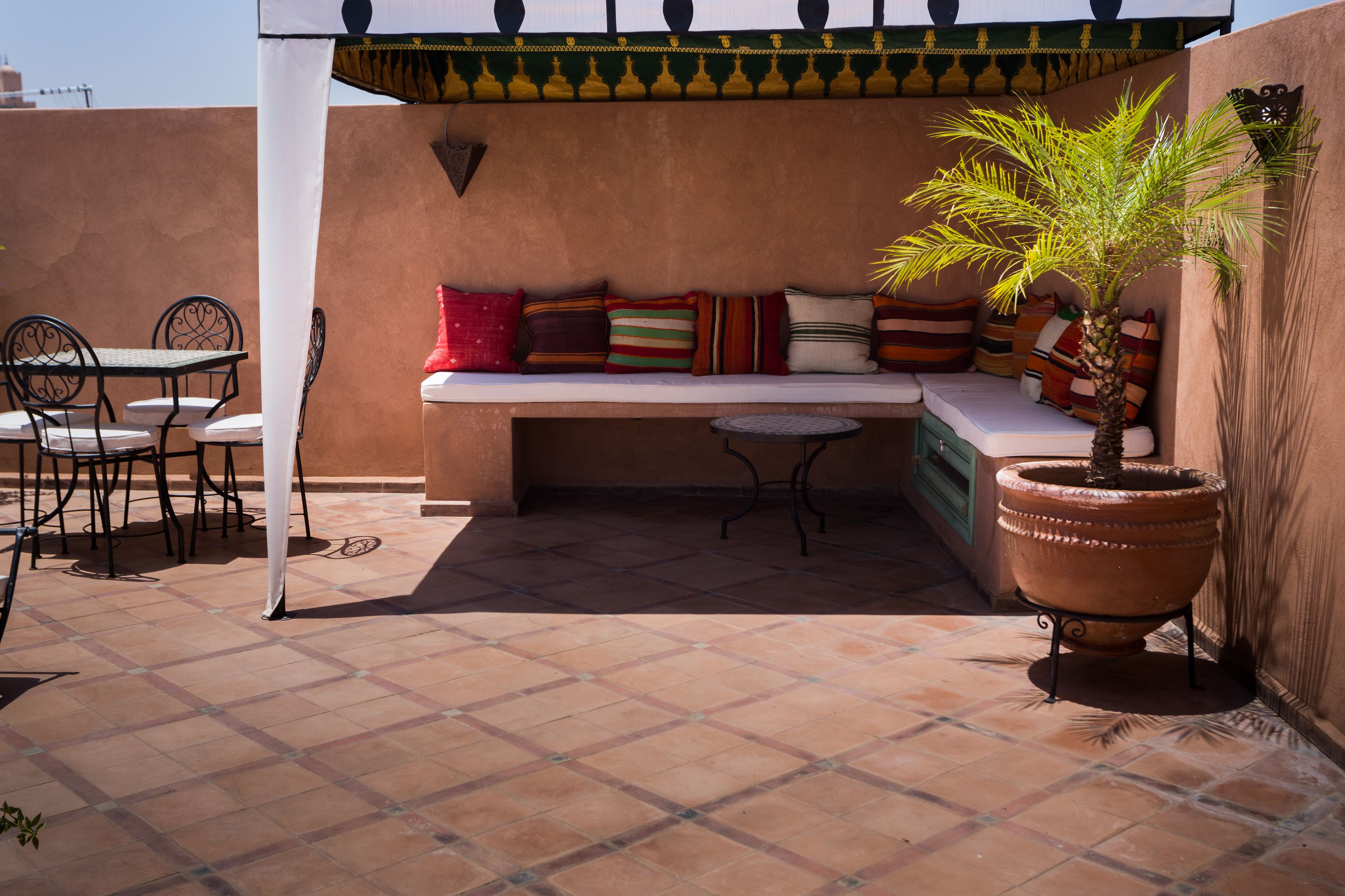 An outdoor patio with a seating area, a table, and a potted plant.