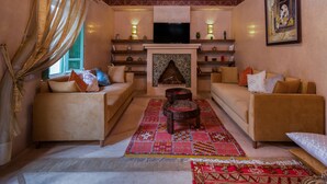 A living room with two sofas, a fireplace, and a television. - Riad Azrur (Marrakech)
