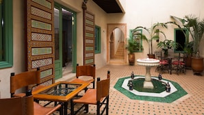 A courtyard with a fountain, chairs, and potted plants. - Riad Azrur (Marrakech)