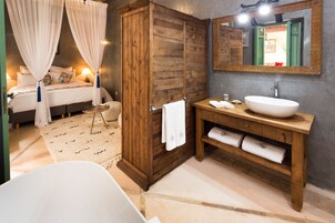 Un dormitorio con cama, armario de madera, baño con lavabo y espejo, y bañera.