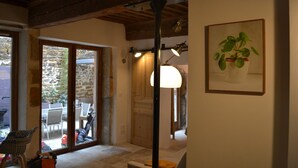 Une pièce avec un plafond en bois, une grande fenêtre, une porte donnant sur l’extérieur et une plante encadrée accrochée au mur.