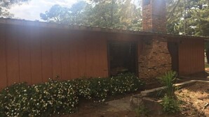 A rustic building with a brick chimney, wooden siding, and a garden with white flowers. - Beautiful Cabin Near Turtle Beach Lodge-ToledoBend Lake-Fishing (Many)