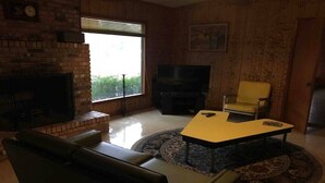 A living room with a brick fireplace, a flat-screen TV, a yellow coffee table, a leather sofa, and a yellow armchair. - Beautiful Cabin Near Turtle Beach Lodge-ToledoBend Lake-Fishing (Many)