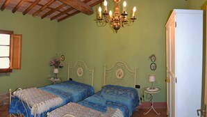 Ein Schlafzimmer mit zwei Betten, einer Kristallleuchter, einem weißen Kühlschrank und einem kleinen Tisch mit einer Lampe.