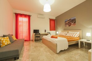 Een hotelkamer met een bed, een bureau, een televisie, een bank en een schilderij aan de muur.