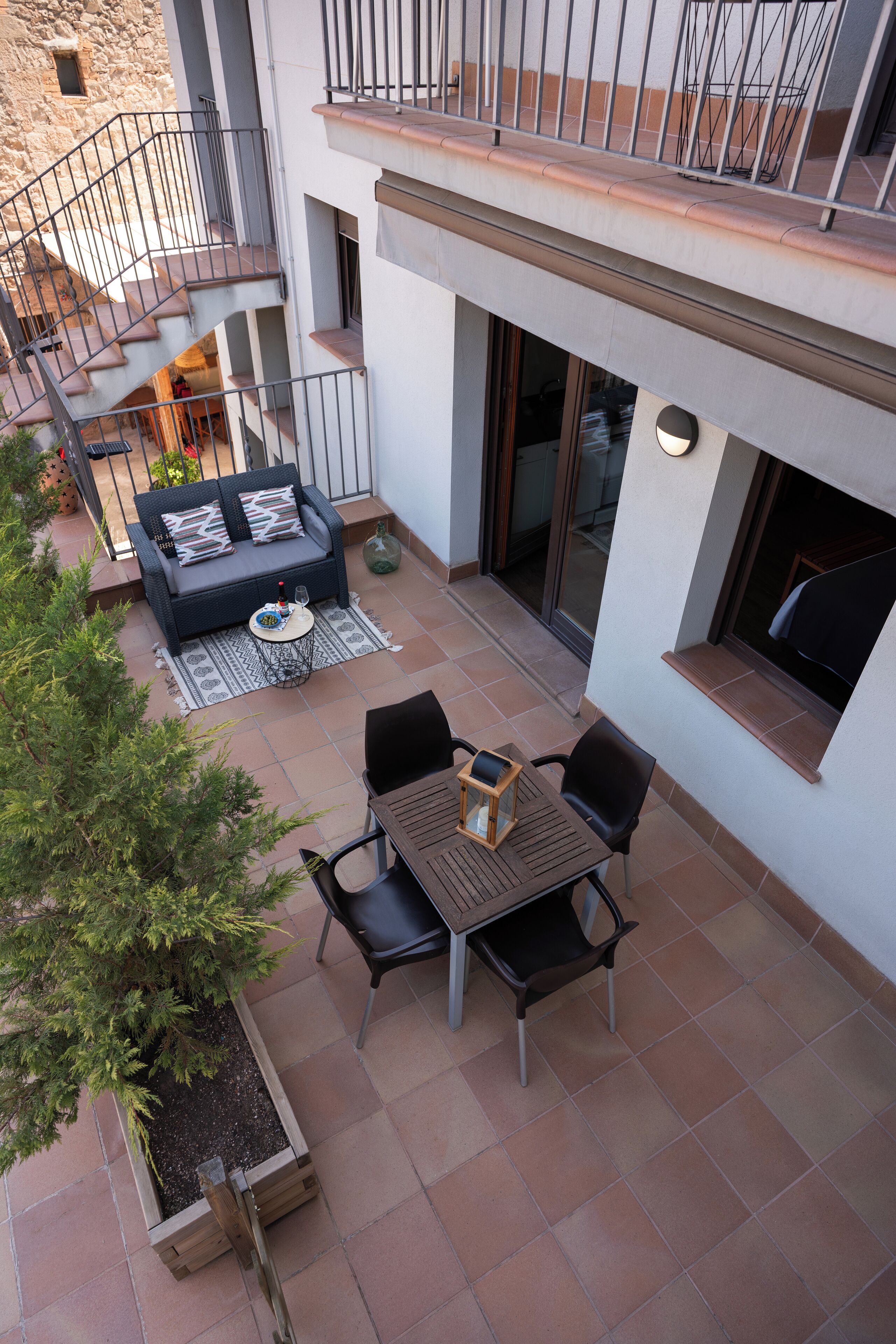 Un patio con sofá, mesa, sillas y una planta en maceta.