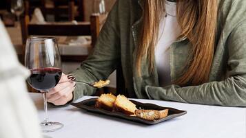 A person sitting at a table with a plate of food and a glass of red wine.