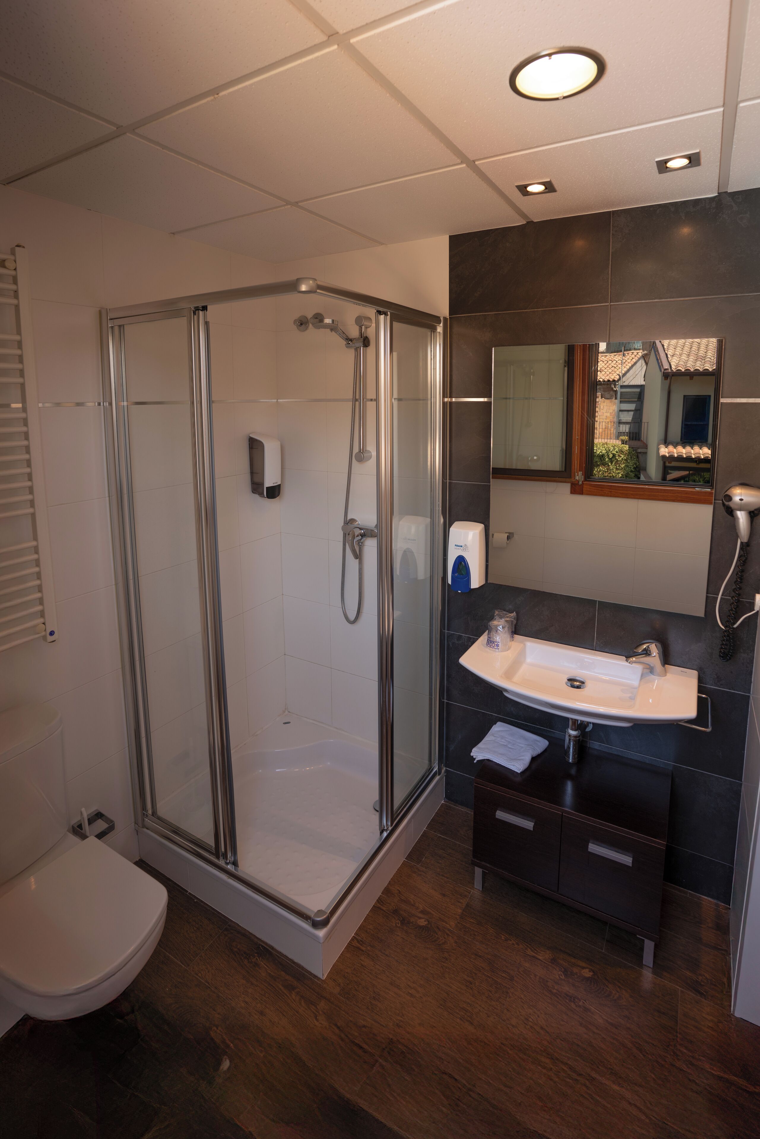 A modern bathroom with a glass-enclosed shower, a white sink, and a dark-toned vanity.