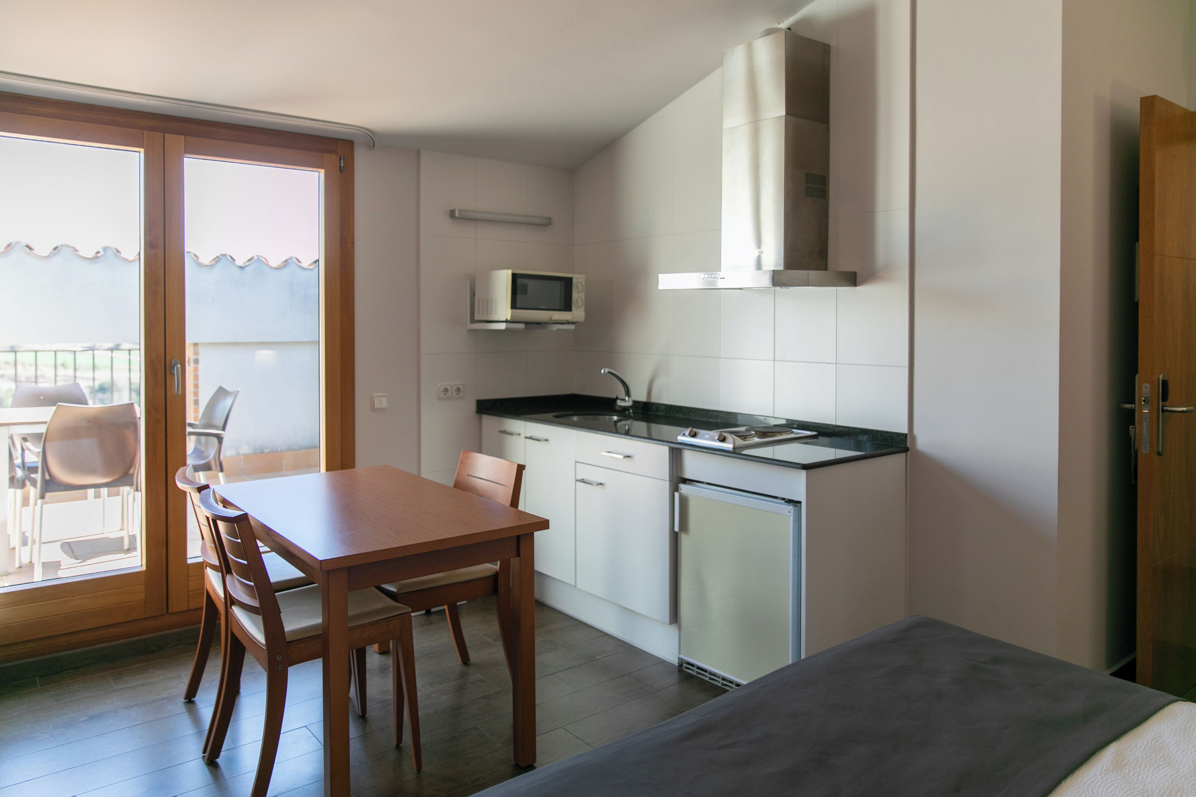 A compact kitchen with a dining area, a microwave, and a small refrigerator.
