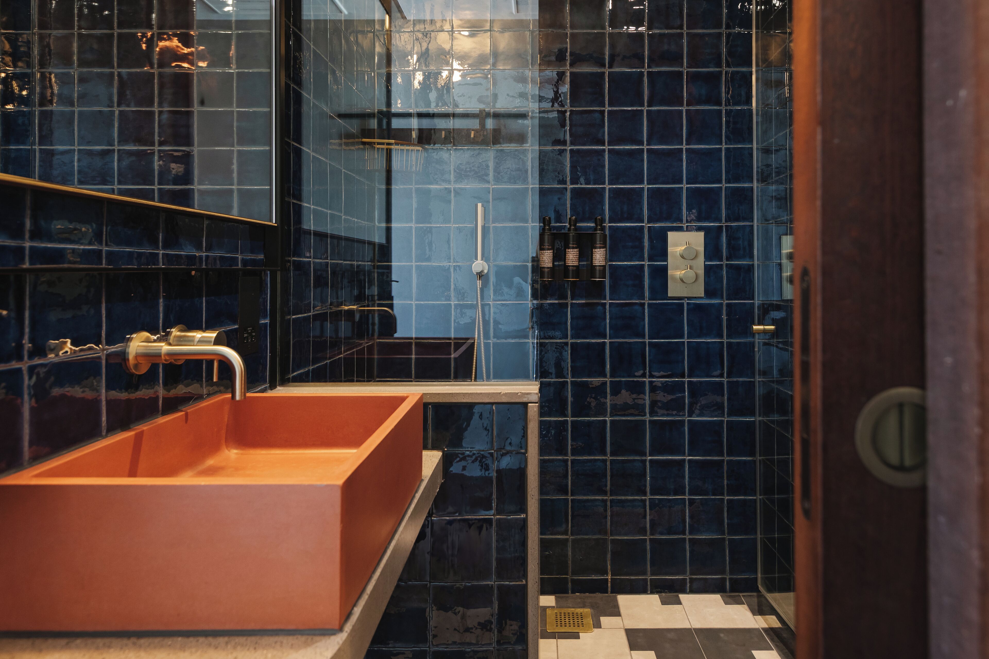 Een badkamer met een groot rechthoekig wastafel, een douchegedeelte en een betegelde muur.