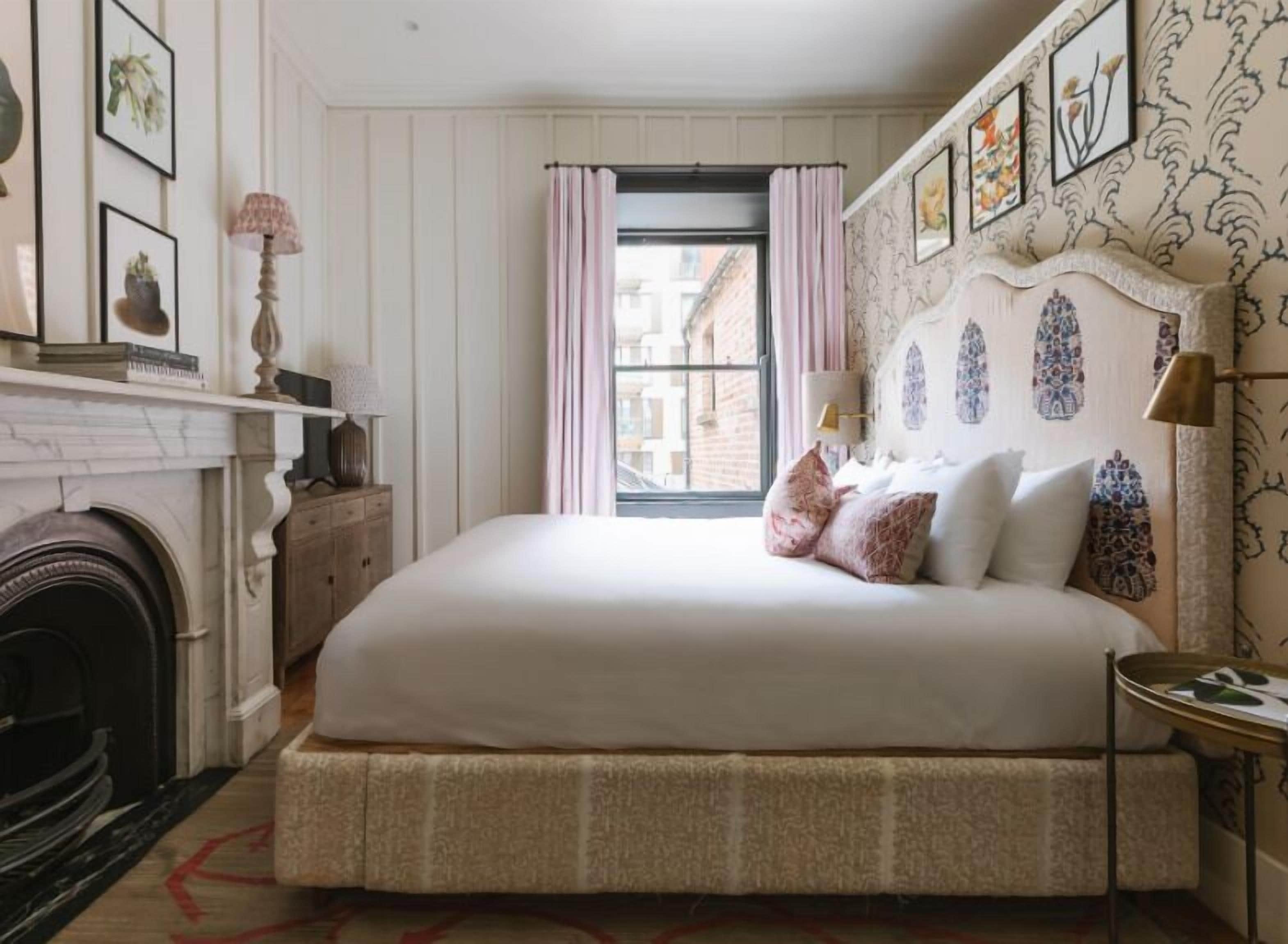 Une chambre à coucher bien aménagée, avec un grand lit, une cheminée et une vue sur la ville par la fenêtre.