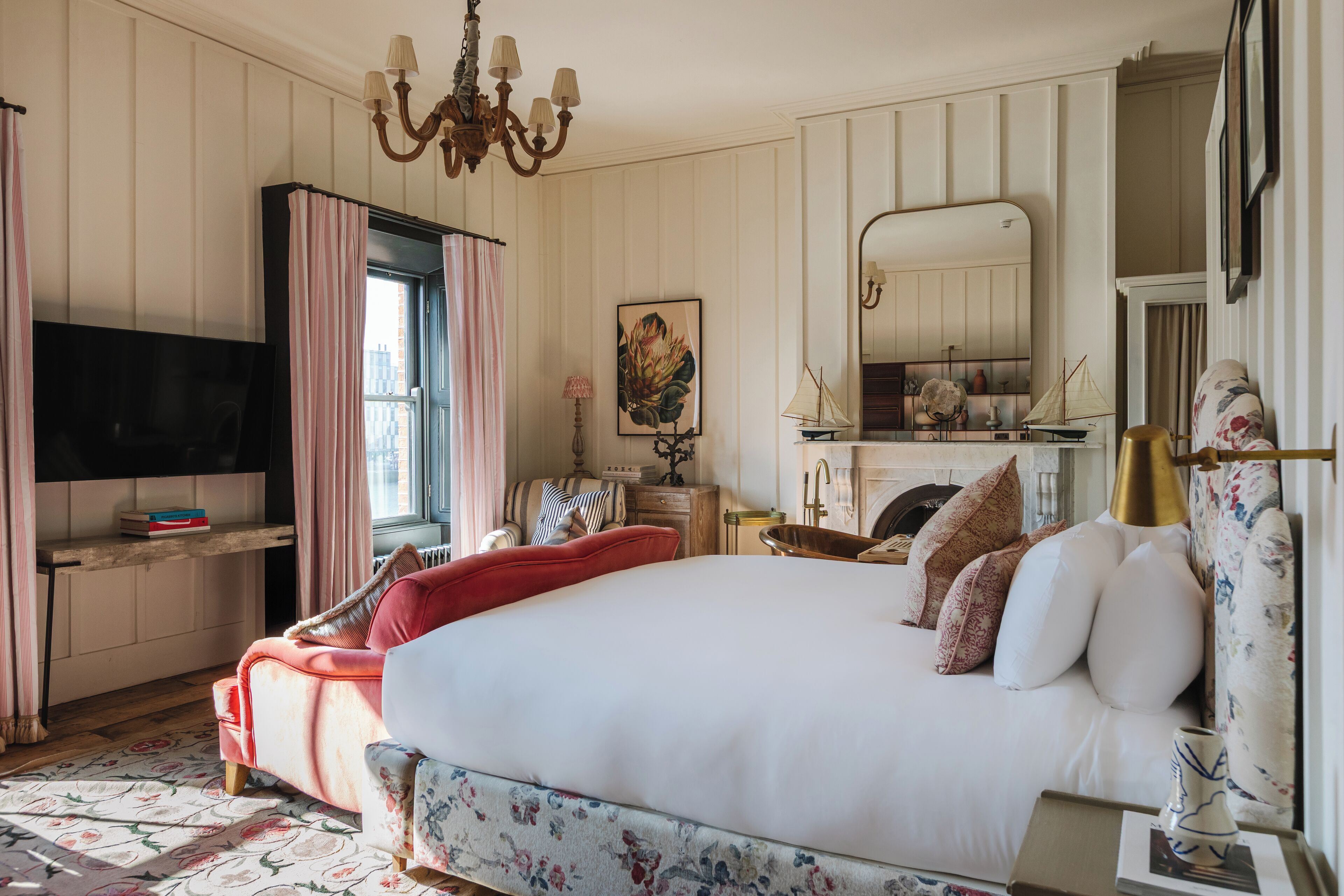 A bedroom with a large bed, a television, a dresser, and a window with curtains.