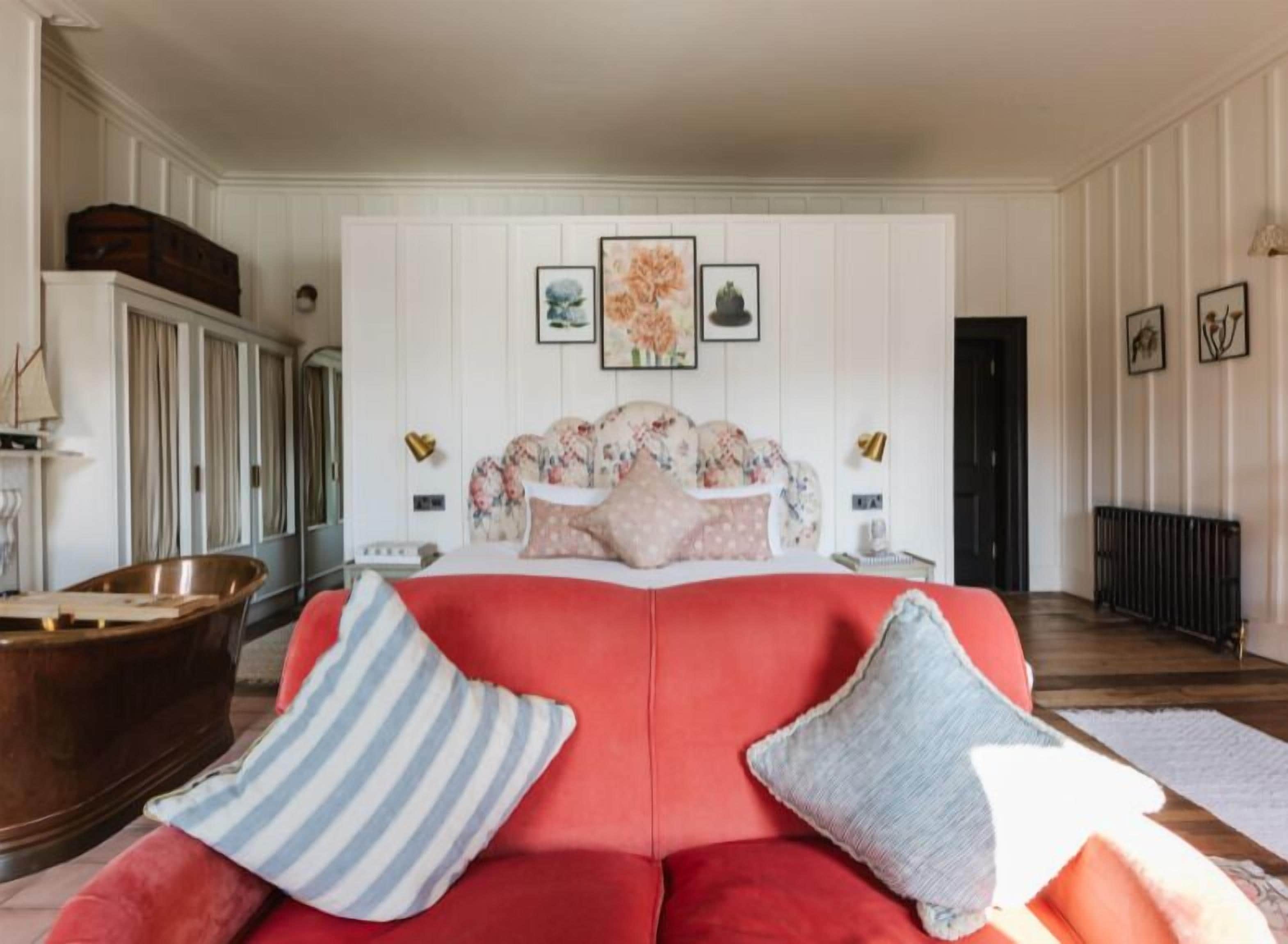 A bedroom with a red sofa, a wooden cabinet, and a radiator.