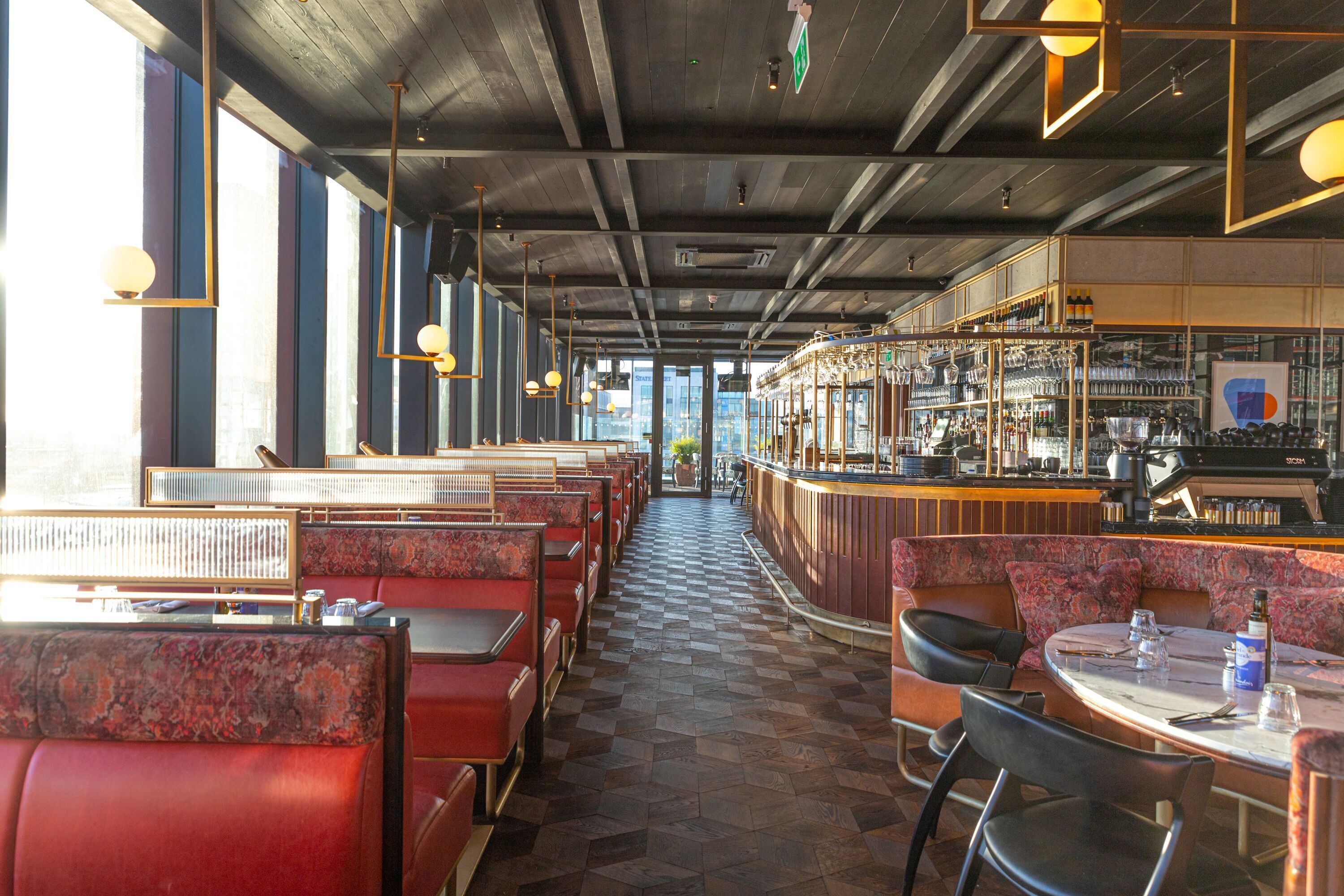 A restaurant with red booths and a bar area.