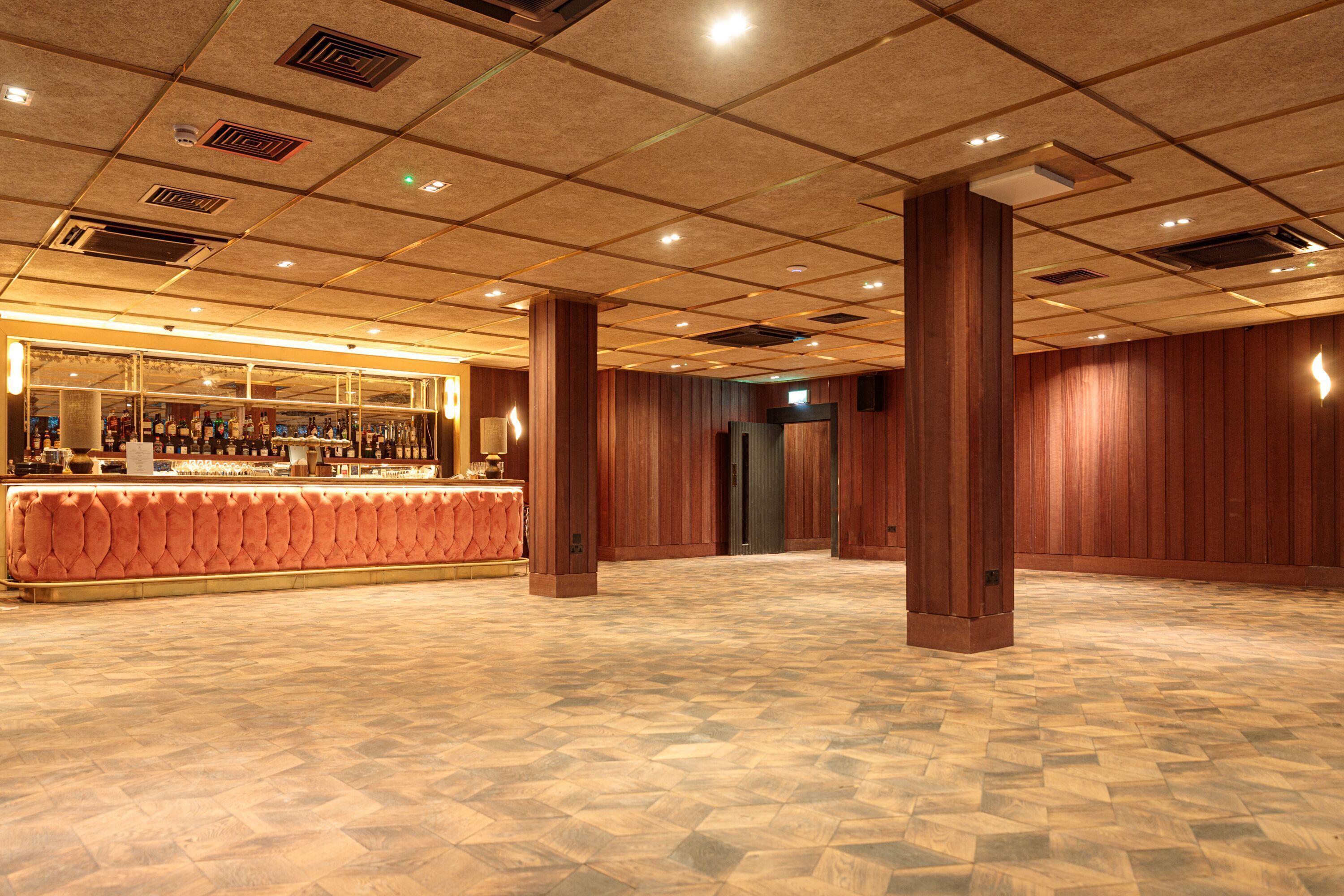 Eine geräumige Lobby mit Barbereich, Holzvertäfelung und einem gemusterten Boden.