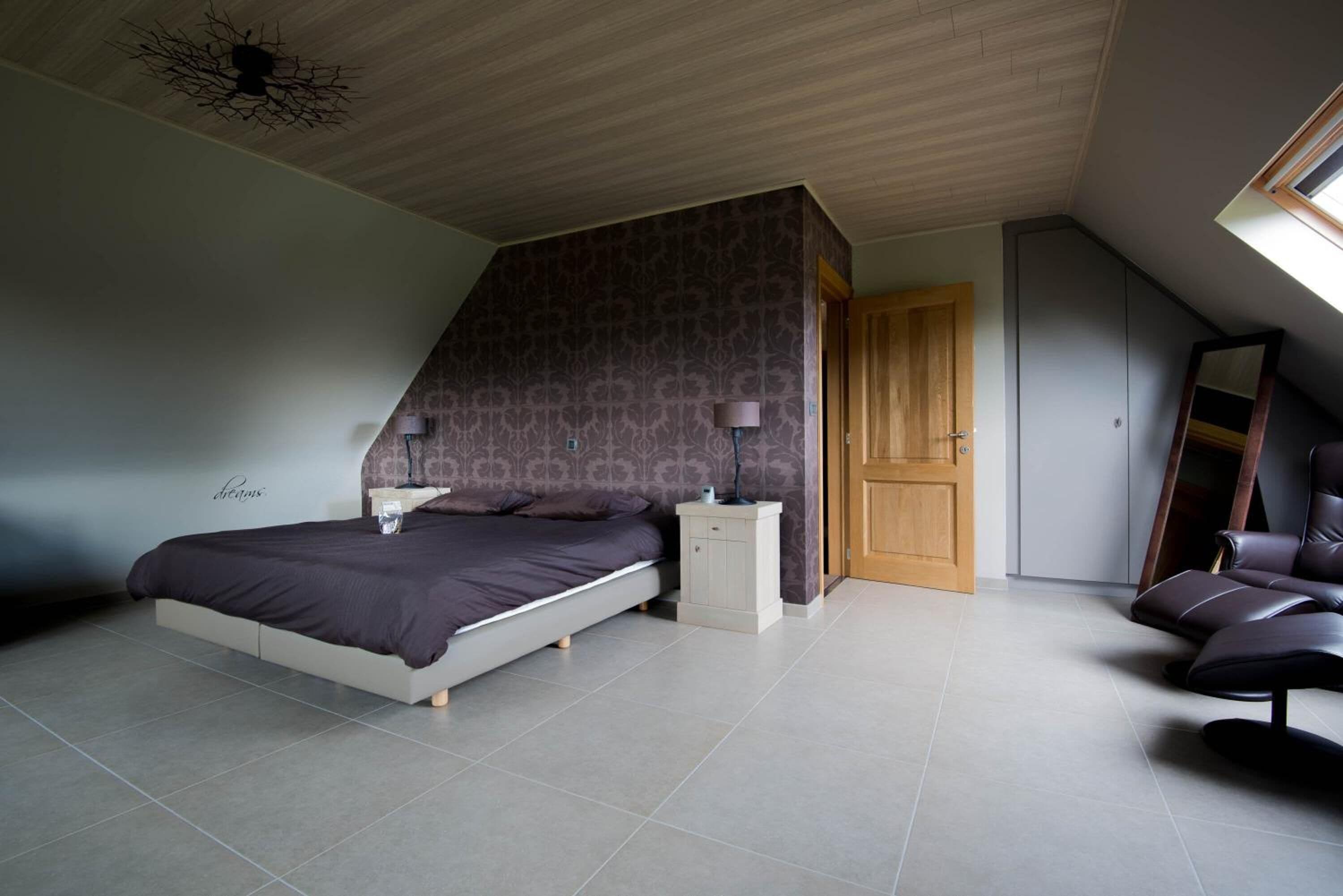 Une chambre à coucher comprenant un lit, des tables de chevet, une armoire et une chaise.