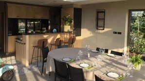Une cuisine moderne dotée d’un coin bar, d’une table à manger pouvant accueillir six personnes et d’une grande fenêtre laissant entrer la lumière naturelle.