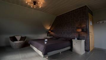 Un dormitorio con cama, mesita de noche, silla y pared con diseño.