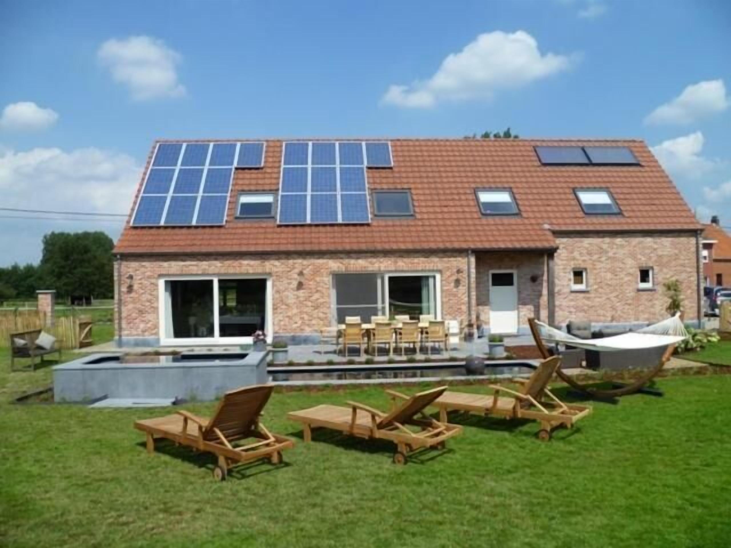 Una casa con techo de tejas, paneles solares, piscina y zona de estar al aire libre.