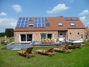 A house with a tiled roof, solar panels, a swimming pool, and outdoor seating. - B&B Welcome Home (Laakdal)
