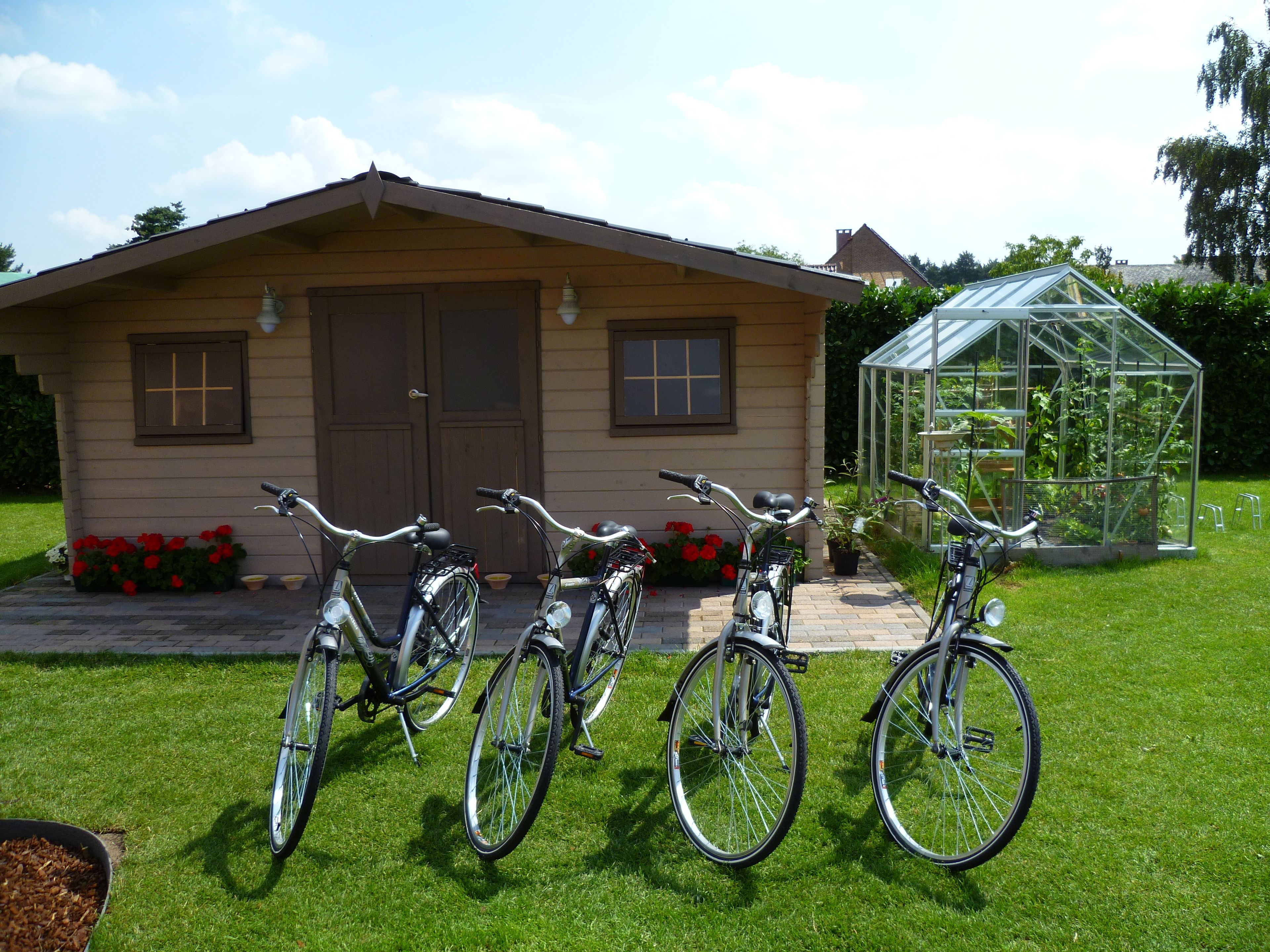 Uma casa com garagem, estufa e três bicicletas estacionadas na frente.