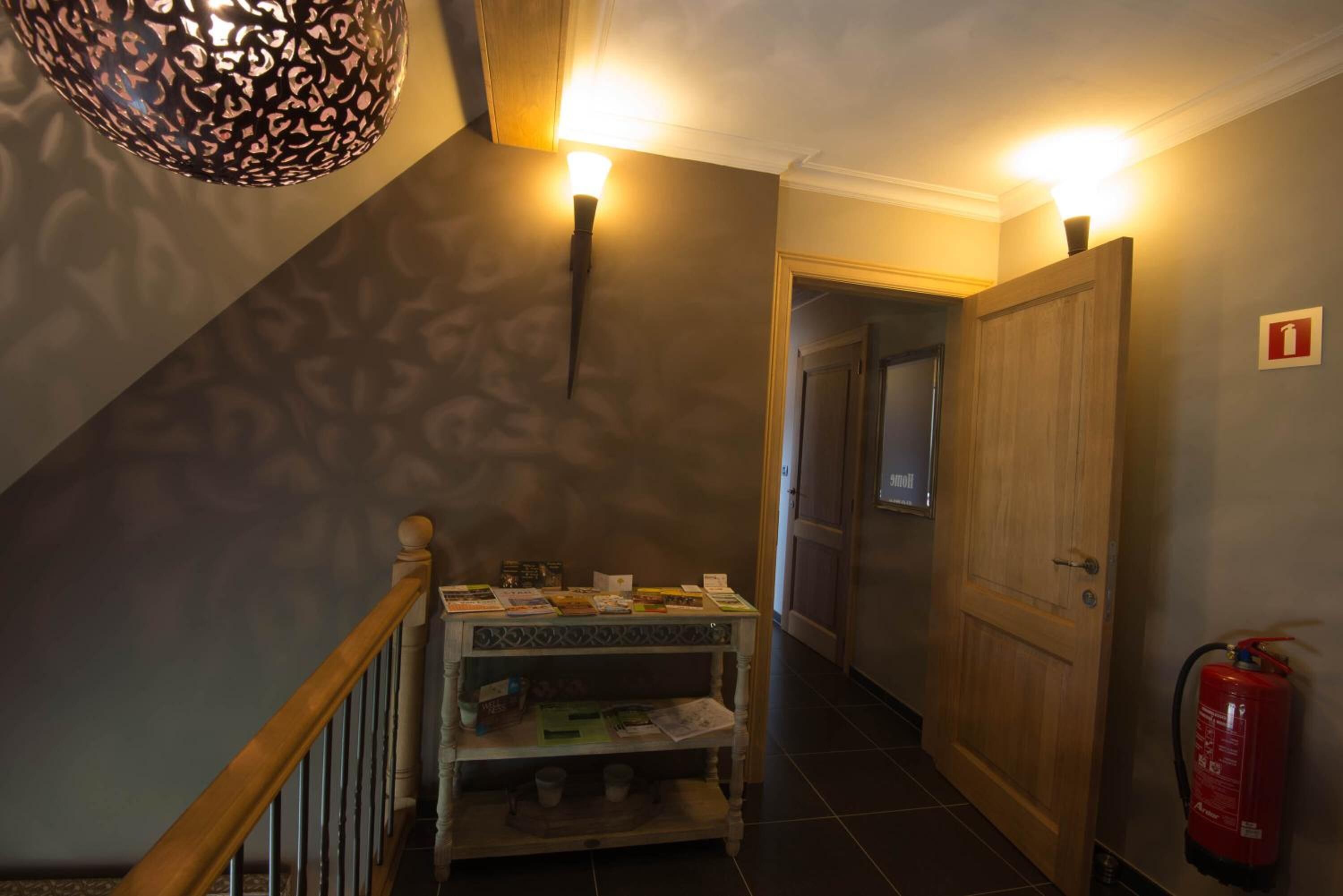 A hallway with a wooden door, a fire extinguisher, and a table with various items.