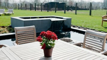 Een terras met twee houten stoelen, een tafel en een bloempot.