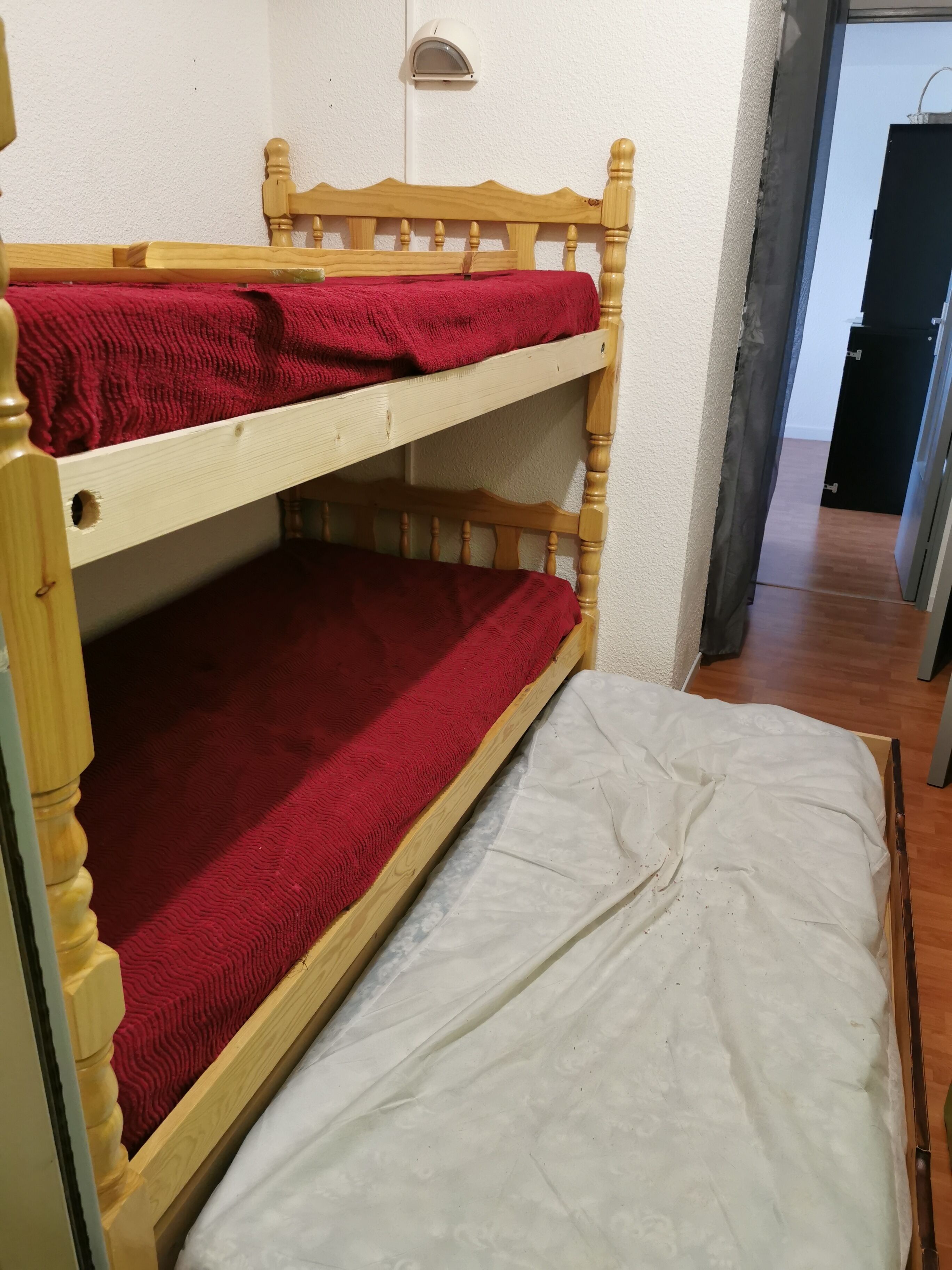Una cama individual con una colcha roja y un colchón blanco.