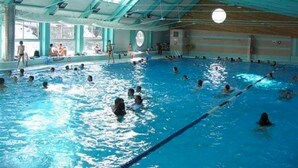 Una piscina interior con varias pistas, ventanas amplias y un techo alto.