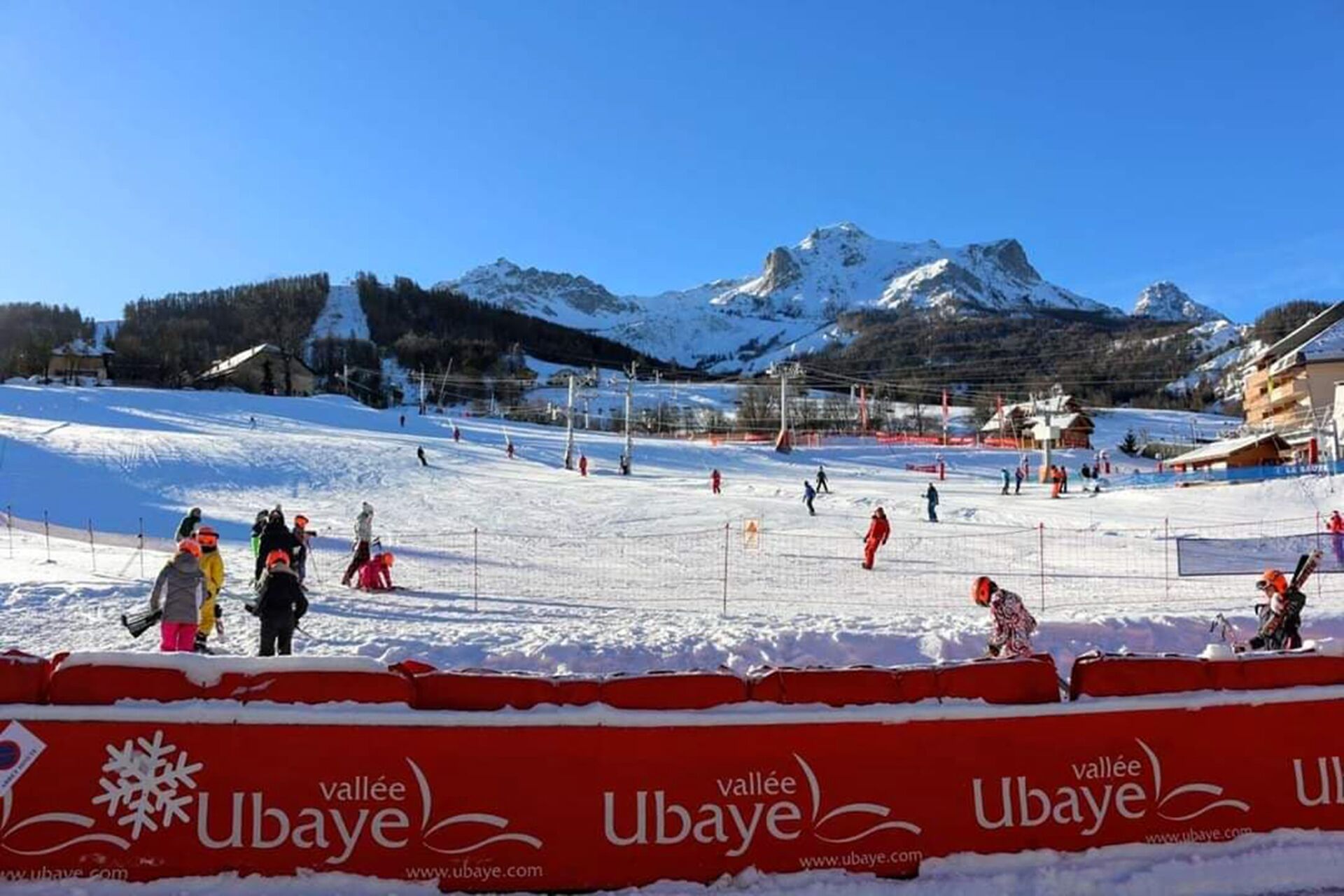 Ein Skigebiet mit blauem Himmel, verschneiten Pisten und einer Bergkulisse.