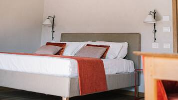 A bedroom with a wooden ceiling, a bed with white bedding and a red blanket, two bedside lamps, and a wooden nightstand.
