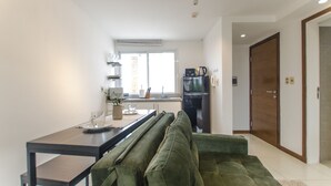 A modern kitchen with a dining area, a green sofa, and a wooden door. - Nuestra Sra. de la Asunción Stylish Loft (Asunción)