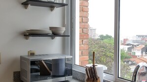 A kitchen with a microwave, a sink, and a window with a view of buildings. - Nuestra Sra. de la Asunción Stylish Loft (Asunción)