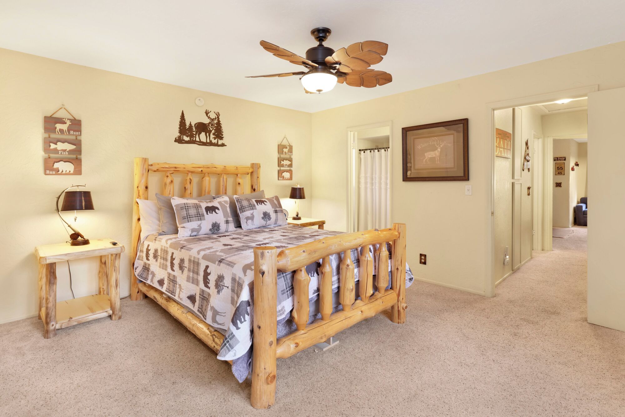 Un dormitorio con una cama de madera, un ventilador de techo y decoraciones en la pared, incluyendo siluetas de animales y una fotografía enmarcada.