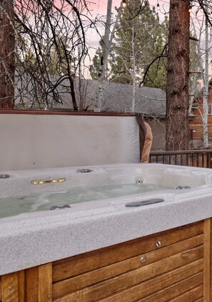 Un bain à remous avec un banc en bois et un mur de pierre en arrière-plan.