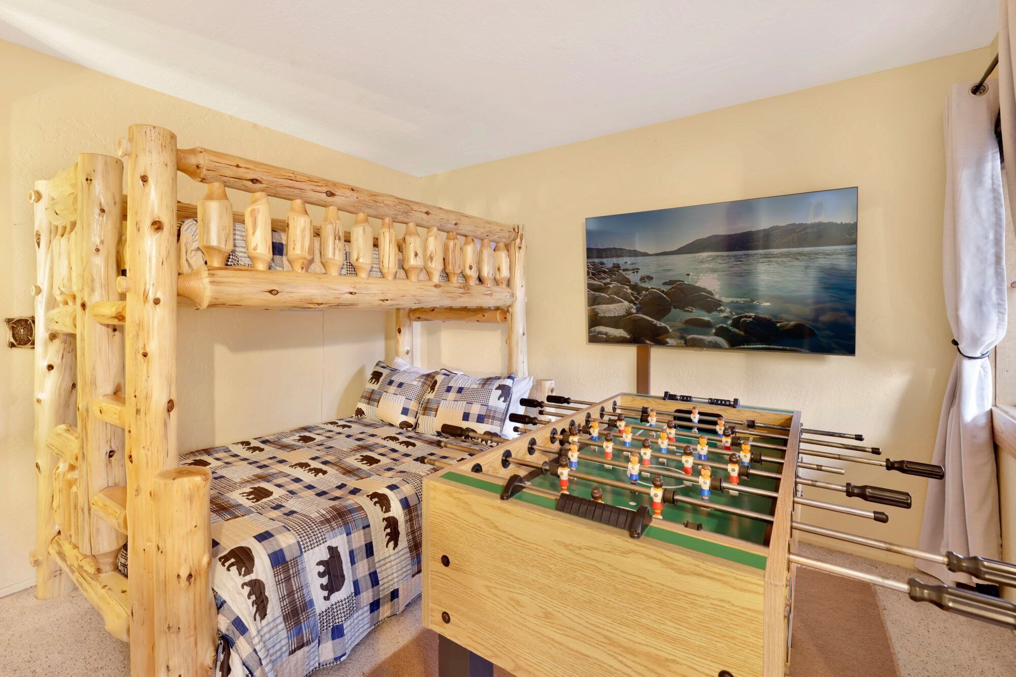 Ein Zimmer mit einem Etagenbett, einem Kicker und einem Gemälde einer Küstenlandschaft.