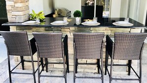 An outdoor kitchen with a stone pillar, a grill, and a TV mounted on the wall.
