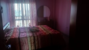 A bedroom with a bed, a dresser, a mirror, and a window with curtains. - At Casa Peppe Partenopeo (Napoli)