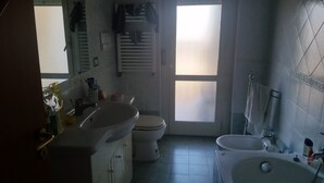 A bathroom with a sink, toilet, and bathtub. There is a window with frosted glass, and a towel rack is visible. - At Casa Peppe Partenopeo (Napoli)