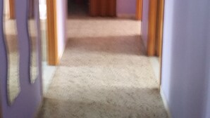 A hallway with purple walls, wooden doors, and a carpeted floor. - At Casa Peppe Partenopeo (Napoli)