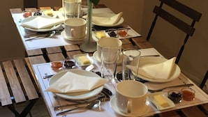 Una mesa de comedor dispuesta con platos, vasos y un florero con una sola rosa.