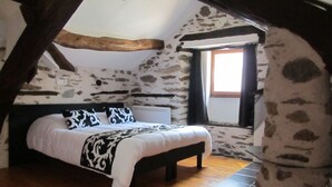Un dormitorio con cama, ventana y paredes de piedra.