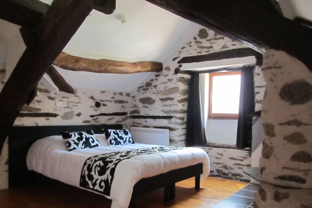 A bedroom with a bed, a window, and stone walls.