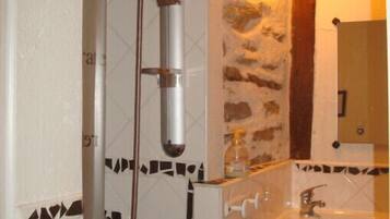 Un bagno con doccia, lavandino e specchio.